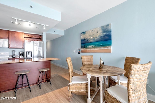 dining area featuring rail lighting and light hardwood / wood-style flooring