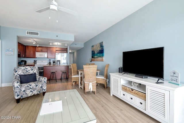 living room with ceiling fan, track lighting, and light hardwood / wood-style floors