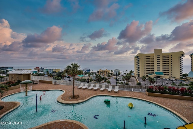 pool at dusk with pool water feature and a patio