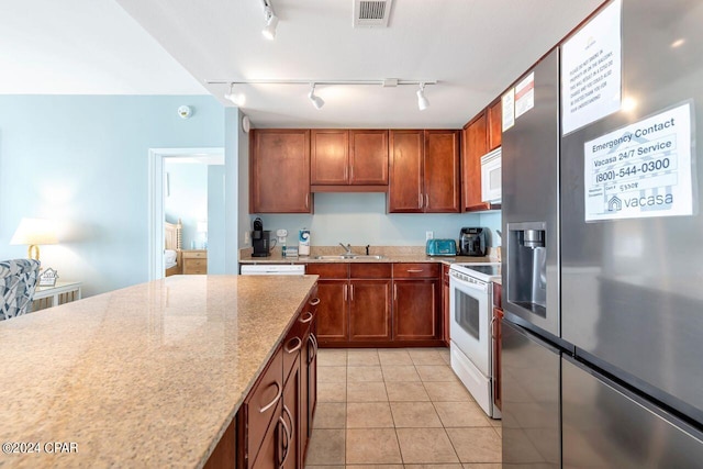 kitchen featuring light stone counters, sink, white appliances, and light tile patterned flooring