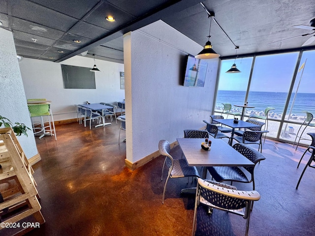 dining room featuring a wall of windows, ceiling fan, and a water view