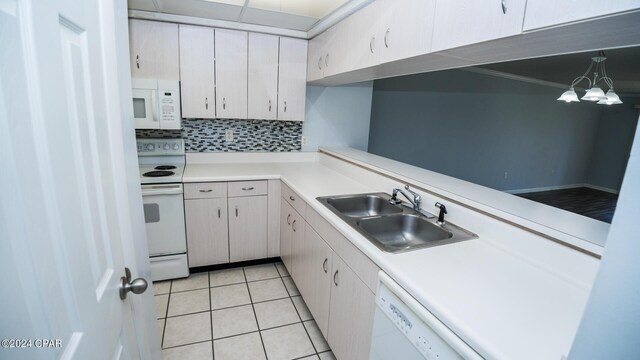 kitchen featuring tasteful backsplash, light tile patterned floors, decorative light fixtures, white appliances, and sink