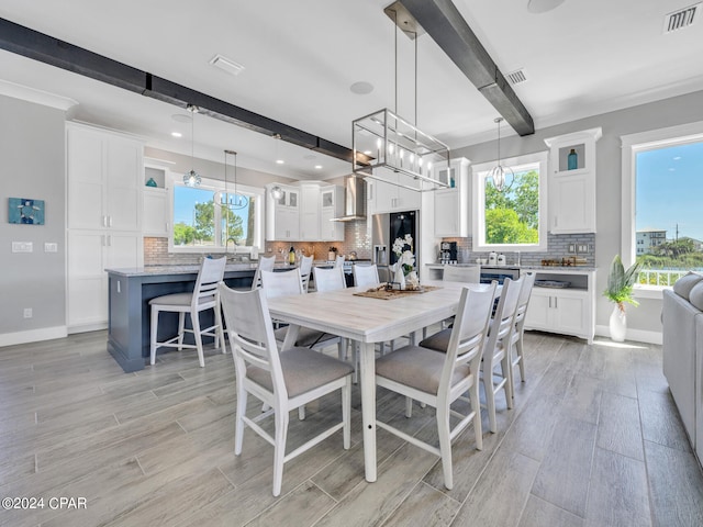 dining space with beamed ceiling, light wood-type flooring, and a wealth of natural light