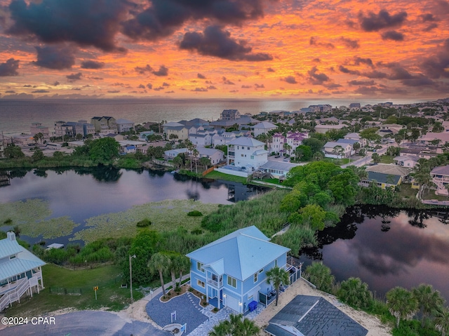 aerial view at dusk featuring a water view