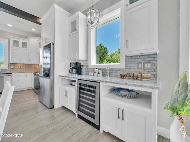 kitchen featuring appliances with stainless steel finishes, white cabinets, backsplash, and wine cooler