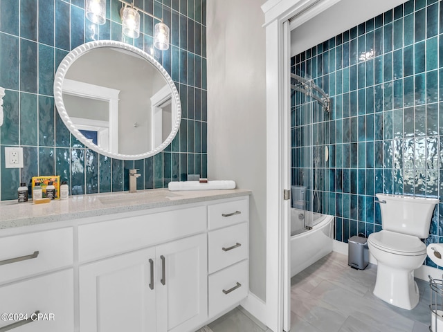 full bathroom with shower / bath combination with glass door, vanity, toilet, and tile walls