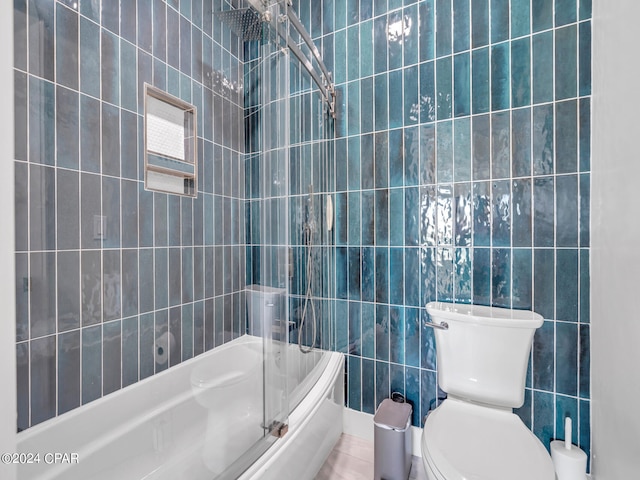 bathroom with tile patterned floors, tiled shower / bath combo, toilet, and tile walls