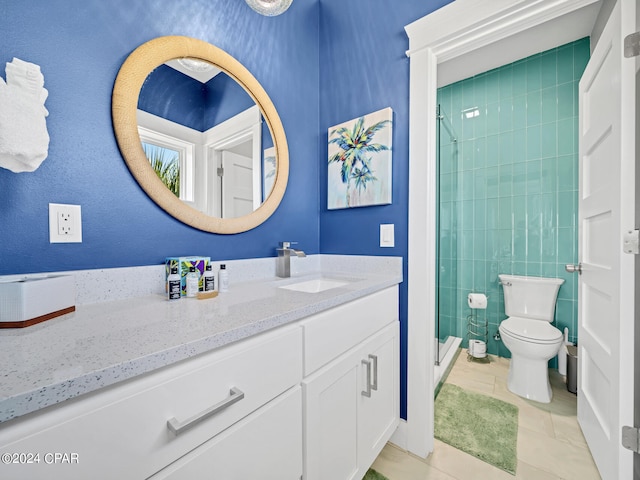 bathroom featuring a tile shower, tile patterned flooring, vanity, and toilet