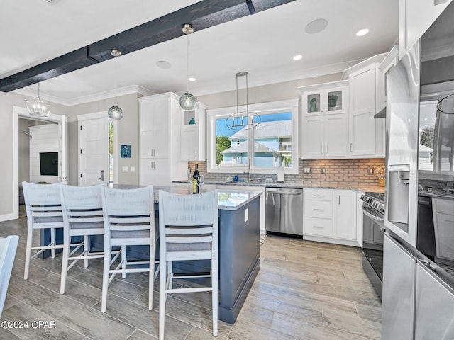 kitchen featuring white cabinets, decorative backsplash, stainless steel appliances, and beamed ceiling