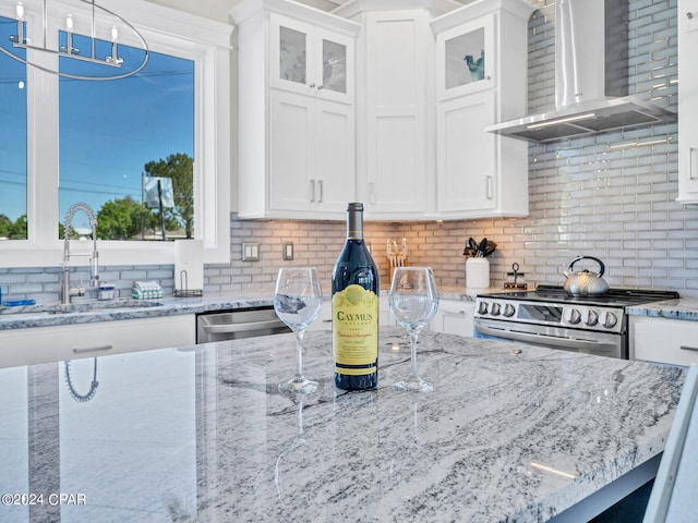 kitchen with white cabinets, sink, wall chimney exhaust hood, decorative backsplash, and stainless steel appliances