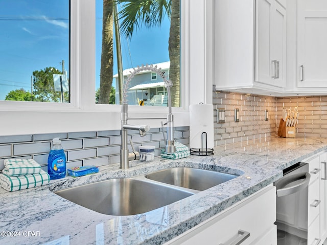 kitchen featuring white cabinetry, sink, tasteful backsplash, light stone counters, and stainless steel dishwasher