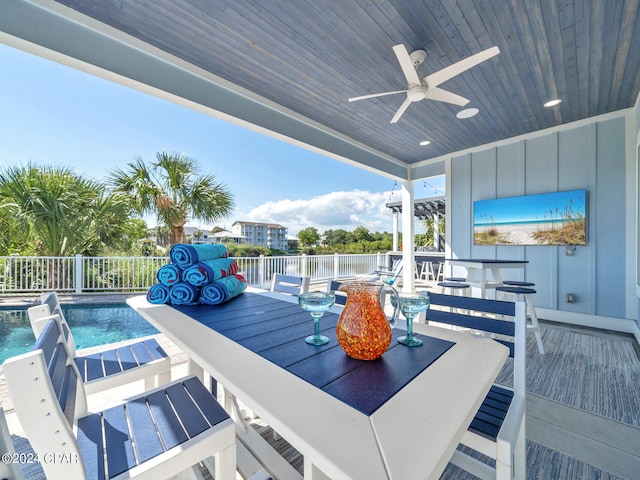 deck with a fenced in pool, ceiling fan, a bar, and pool water feature