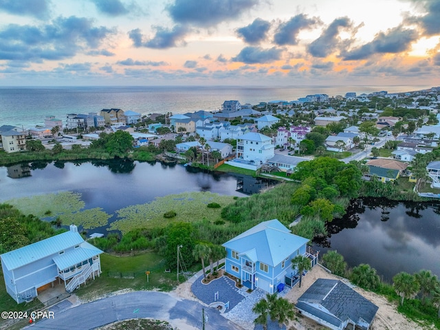 aerial view at dusk featuring a water view