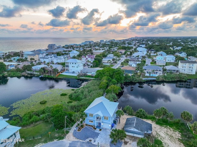 aerial view at dusk featuring a water view