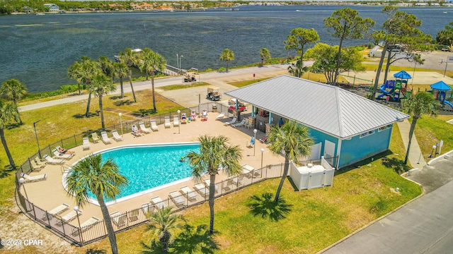 view of swimming pool with a lawn, a water view, and a patio area