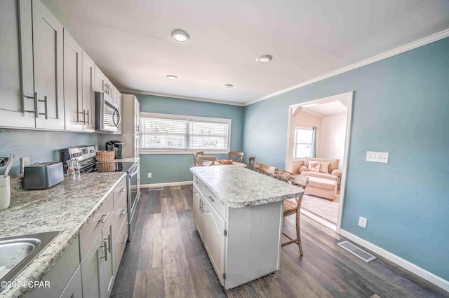 kitchen with dark hardwood / wood-style floors, sink, a kitchen island, appliances with stainless steel finishes, and a breakfast bar area