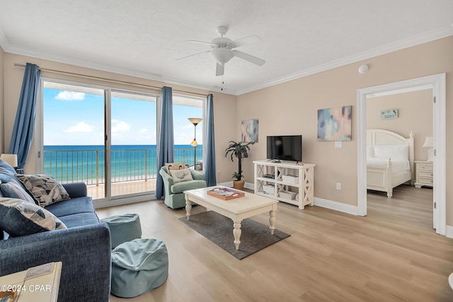 living room with a textured ceiling, light hardwood / wood-style floors, ornamental molding, a water view, and ceiling fan