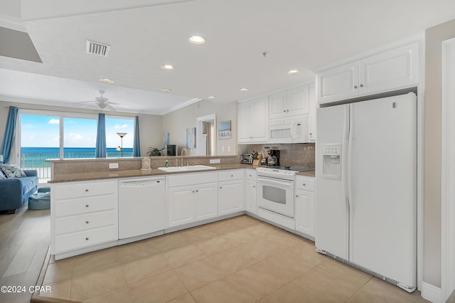 kitchen with white cabinetry, kitchen peninsula, white appliances, a water view, and sink