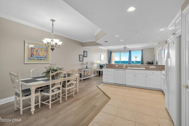 5004 Thomas Dr Unit 1209, Panama City Beach, FL 32408 - kitchen featuring white appliances, a peninsula, a sink, ornamental molding, and white cabinets
