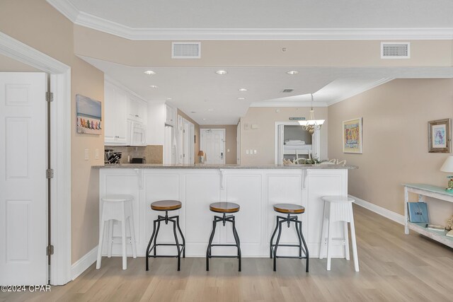 5004 Thomas Dr Unit 1209, Panama City Beach, FL 32408 - kitchen with light wood-type flooring, visible vents, a kitchen breakfast bar, and a peninsula