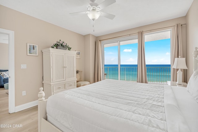 bedroom with light wood-type flooring, ceiling fan, a water view, and access to outside