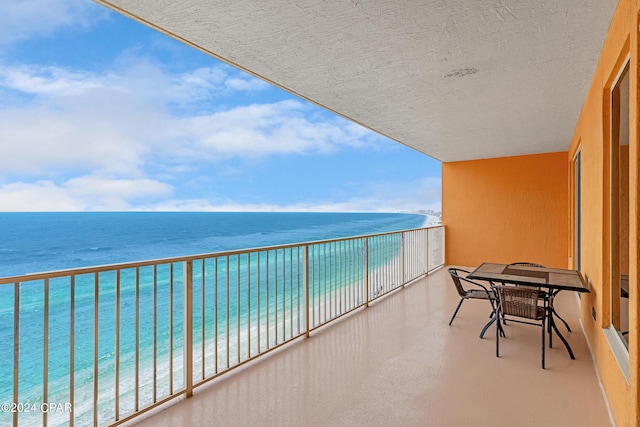 balcony with a water view and a view of the beach