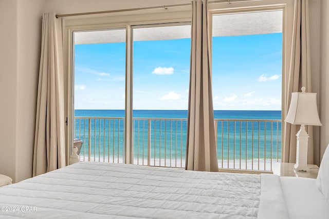 unfurnished bedroom with a water view, access to outside, and a beach view