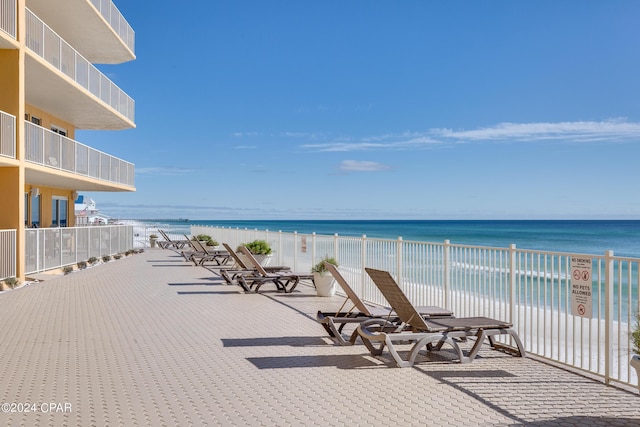 view of patio / terrace with a water view and a beach view