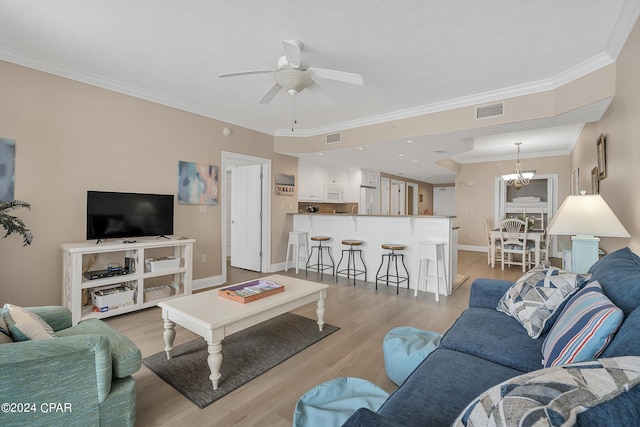 living room with light hardwood / wood-style floors, ornamental molding, and ceiling fan with notable chandelier