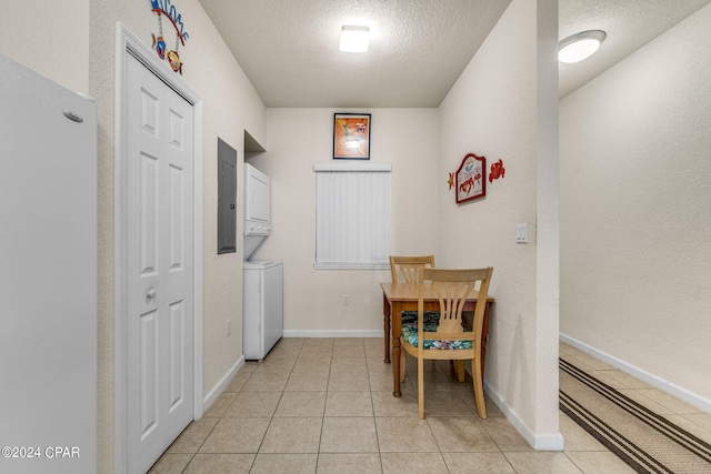 interior space with stacked washer and dryer, a textured ceiling, and light tile floors