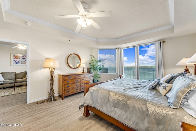 bedroom with light hardwood / wood-style floors, access to exterior, ceiling fan, ornamental molding, and a raised ceiling