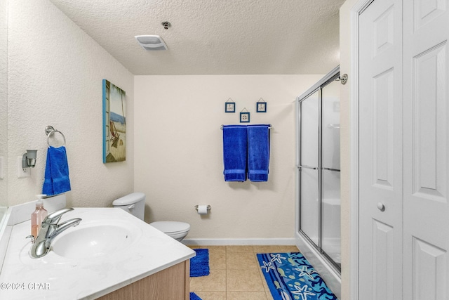 bathroom featuring toilet, tile flooring, a shower with shower door, vanity, and a textured ceiling