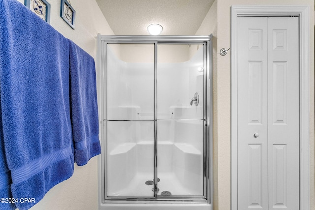 bathroom featuring an enclosed shower and a textured ceiling