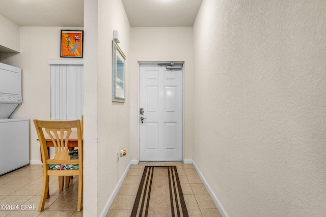 corridor featuring stacked washer and clothes dryer and light tile floors