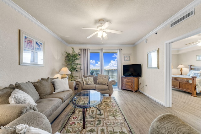 living room with ceiling fan, crown molding, a textured ceiling, and light wood-type flooring