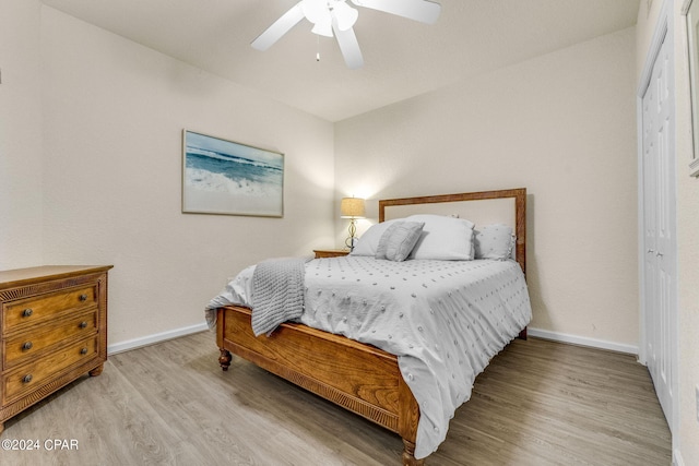 bedroom with a closet, light hardwood / wood-style floors, and ceiling fan