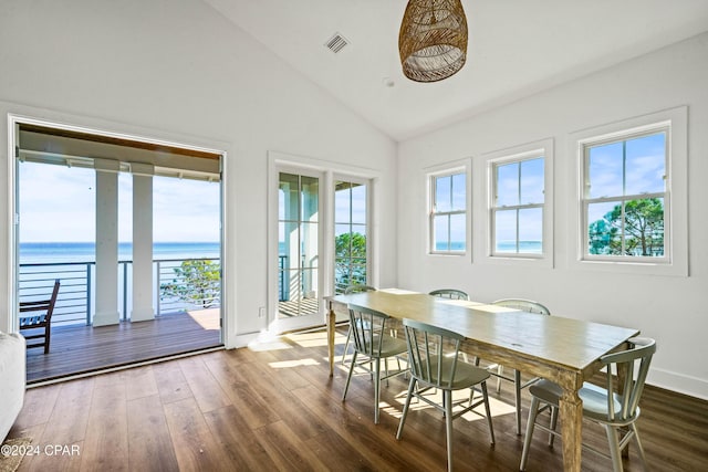 dining area featuring dark hardwood / wood-style flooring, a water view, and vaulted ceiling