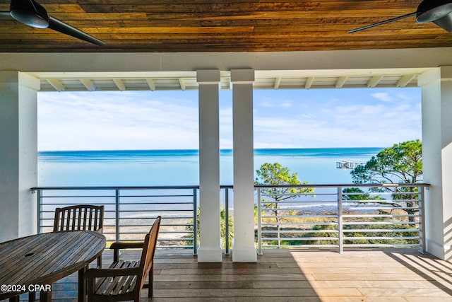 wooden deck featuring ceiling fan, a water view, and a beach view