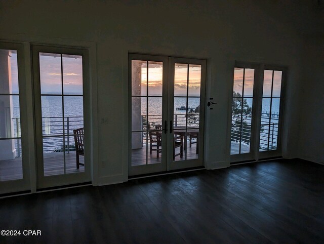 doorway with dark hardwood / wood-style floors, a water view, and french doors