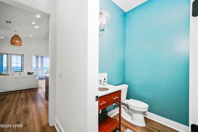 bathroom featuring wood-type flooring, vanity, an inviting chandelier, and toilet