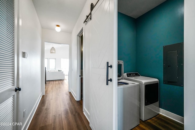 washroom featuring dark hardwood / wood-style flooring, a barn door, electric panel, and washing machine and dryer