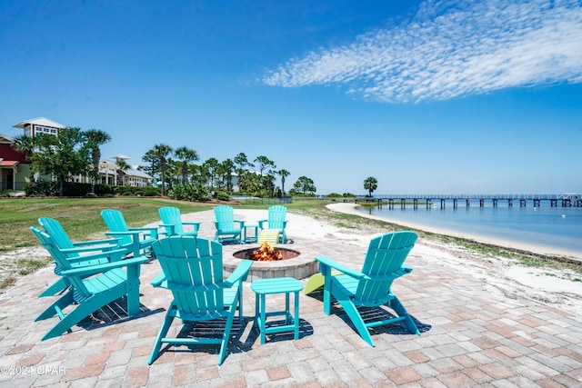 view of patio with a fire pit, a water view, and a view of the beach