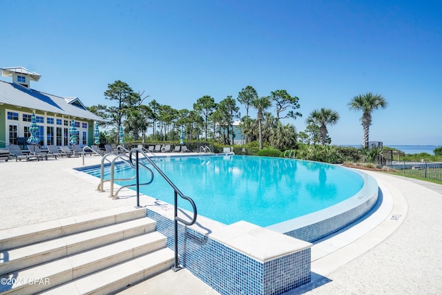 view of swimming pool featuring a water view and a patio