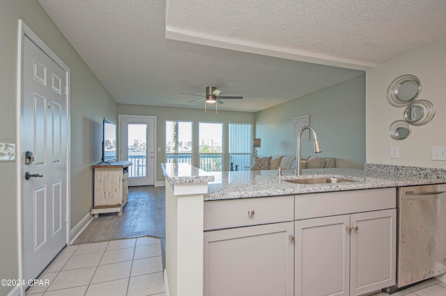 kitchen with light stone counters, ceiling fan, light wood-type flooring, dishwasher, and sink