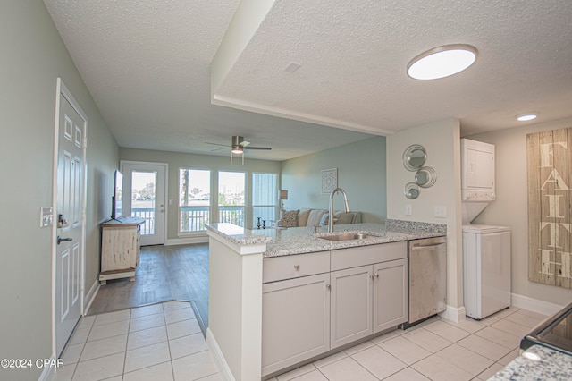 kitchen featuring ceiling fan, sink, light wood-type flooring, stacked washer and clothes dryer, and stainless steel dishwasher