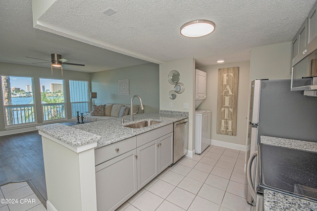 kitchen featuring appliances with stainless steel finishes, ceiling fan, gray cabinetry, sink, and stacked washer / dryer