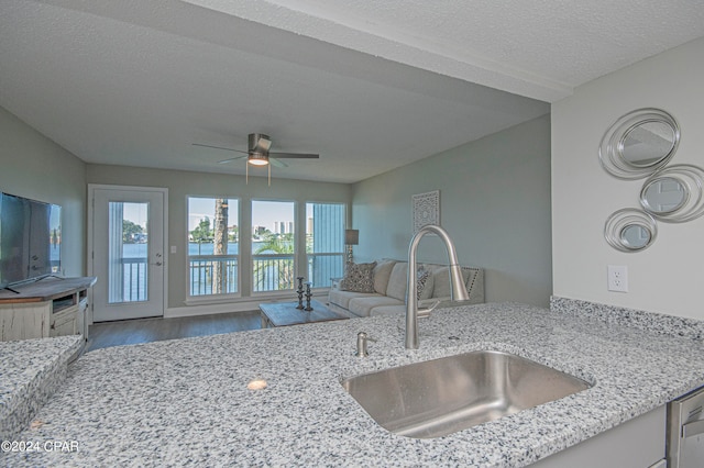 kitchen with ceiling fan, sink, light hardwood / wood-style flooring, a textured ceiling, and light stone counters