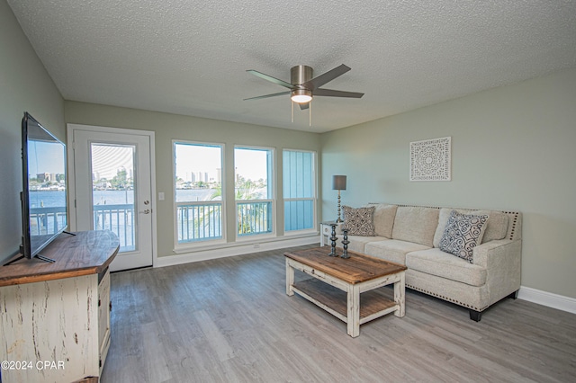 living room with a textured ceiling, ceiling fan, and hardwood / wood-style flooring