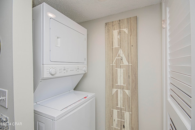 laundry room with a textured ceiling and stacked washer / dryer