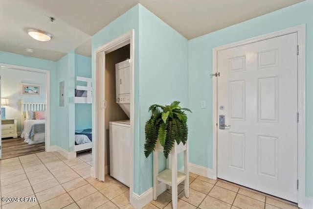 foyer with stacked washing maching and dryer and light tile floors